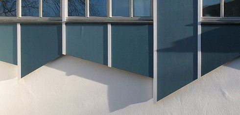 Blaue und weiße Gebäudefassade mit geometrischen Formen und Fenstern.