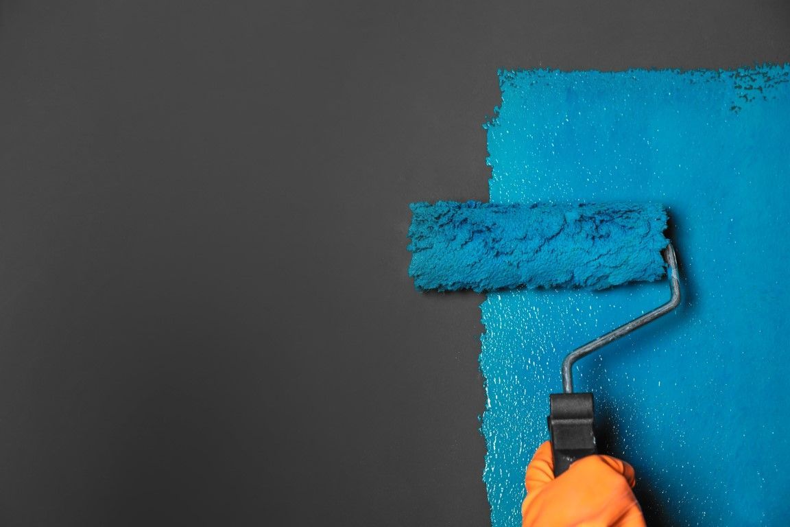a close up of a paint roller painting a black wall, blue