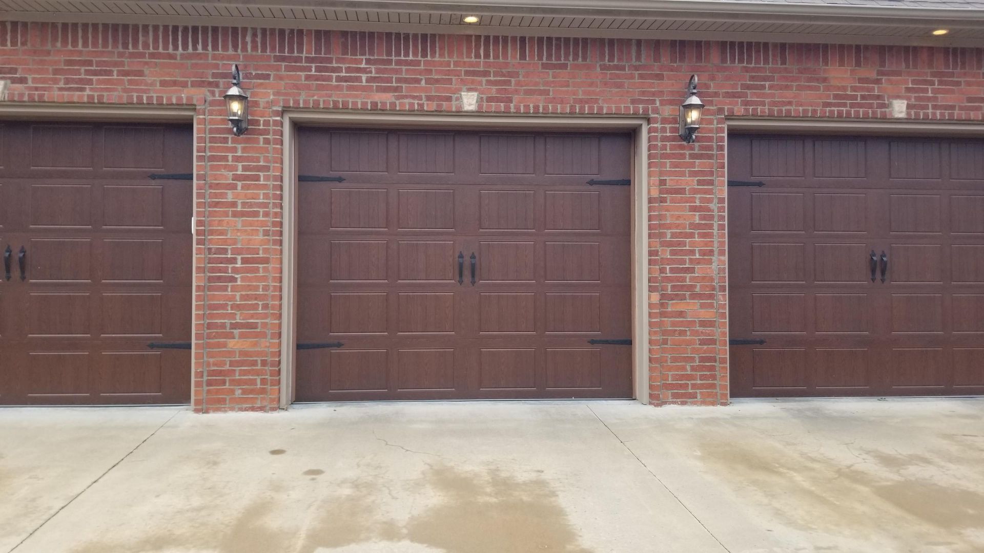 A row of brown garage doors on a brick building.
