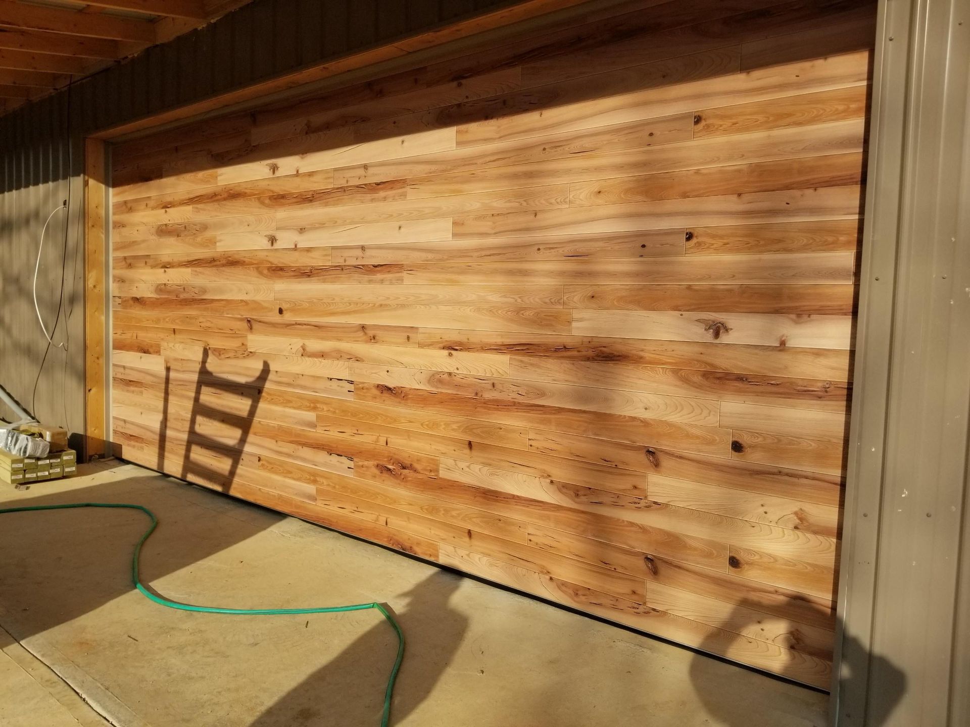 A wooden garage door with a green hose attached to it