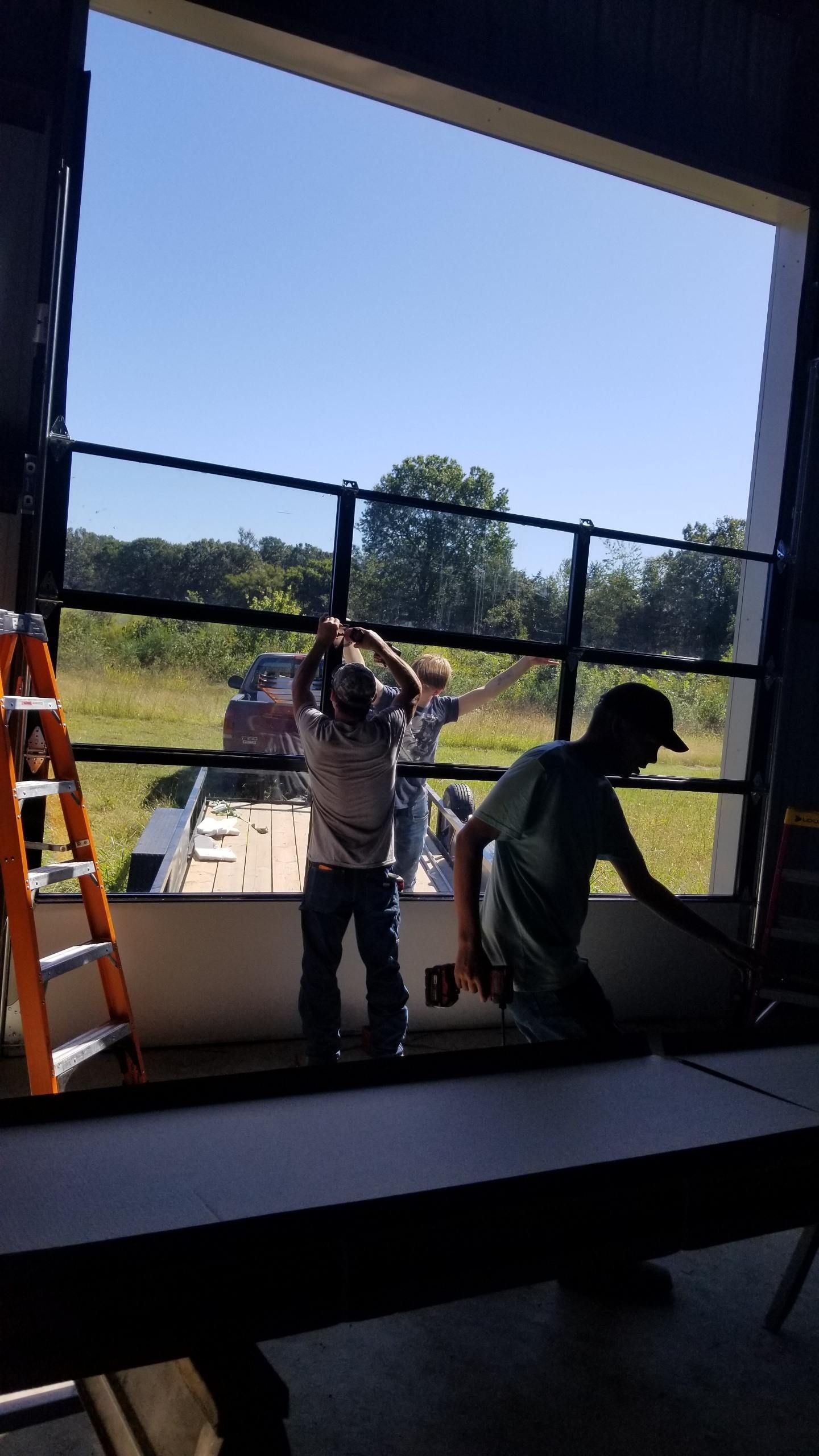 Two men are working on a garage door.