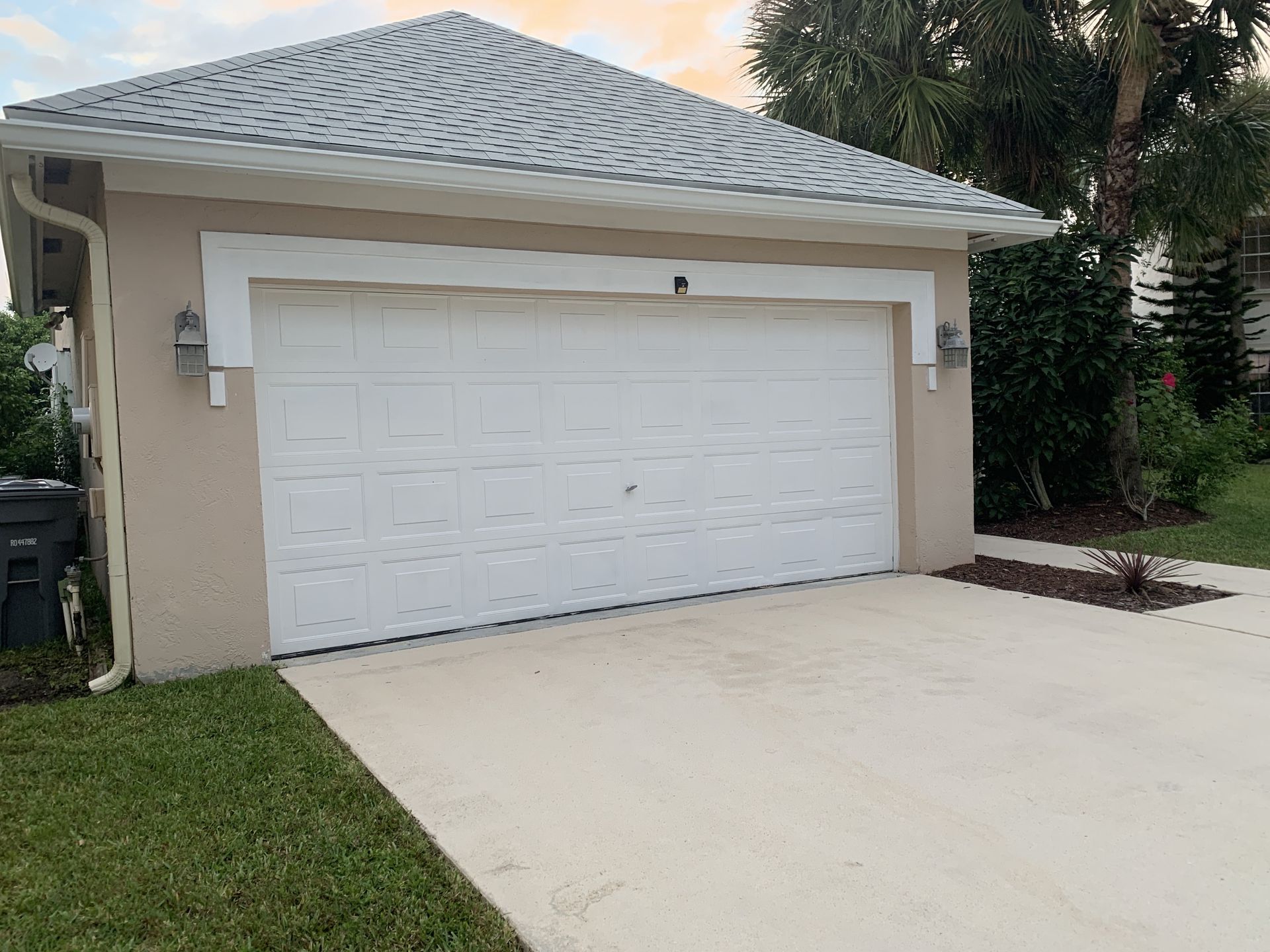 A white garage door is sitting in front of a house.