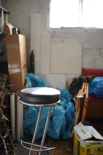 A bar stool is sitting in a room filled with boxes and bags.