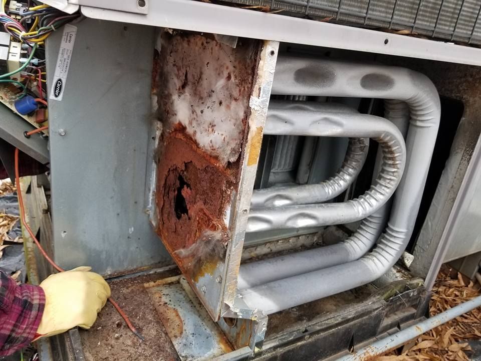 A person is working on a rusty air conditioner.