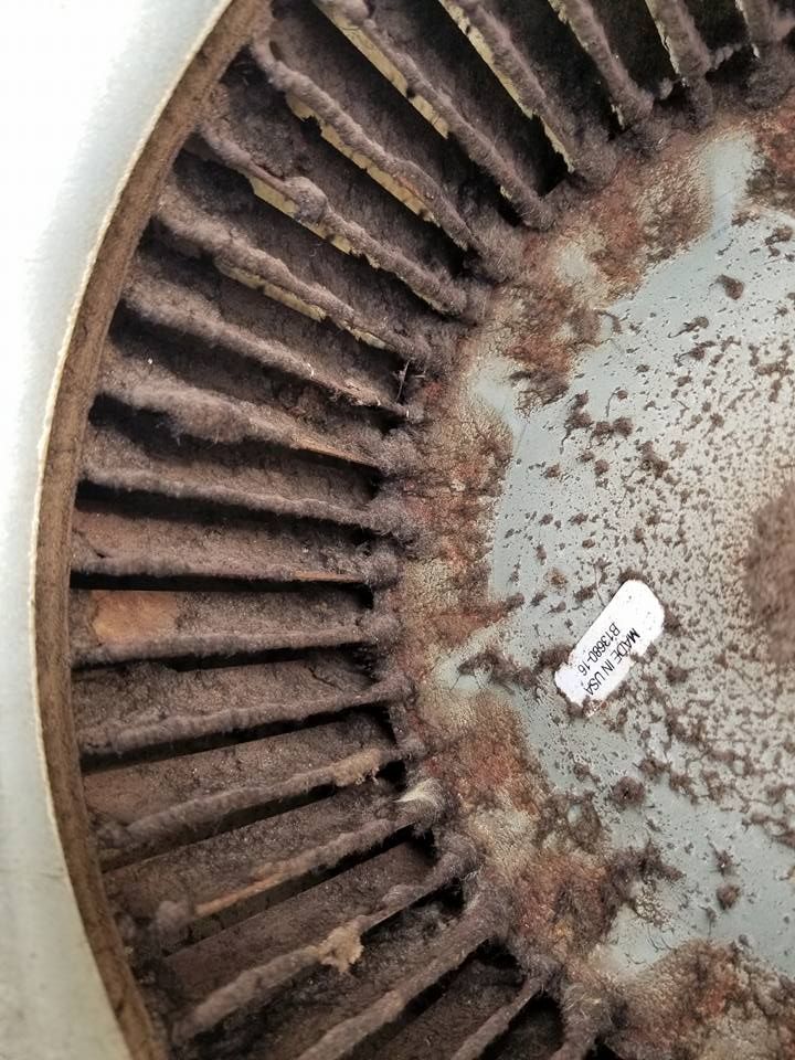 A close up of a rusty fan with a tag on it.
