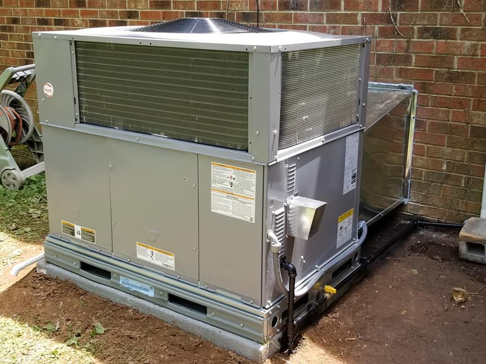 A large air conditioner is sitting outside of a brick building.
