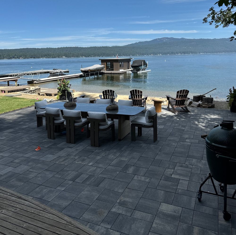 A patio with a table and chairs overlooking a body of water A patio with a table and chairs overlooking a body of water