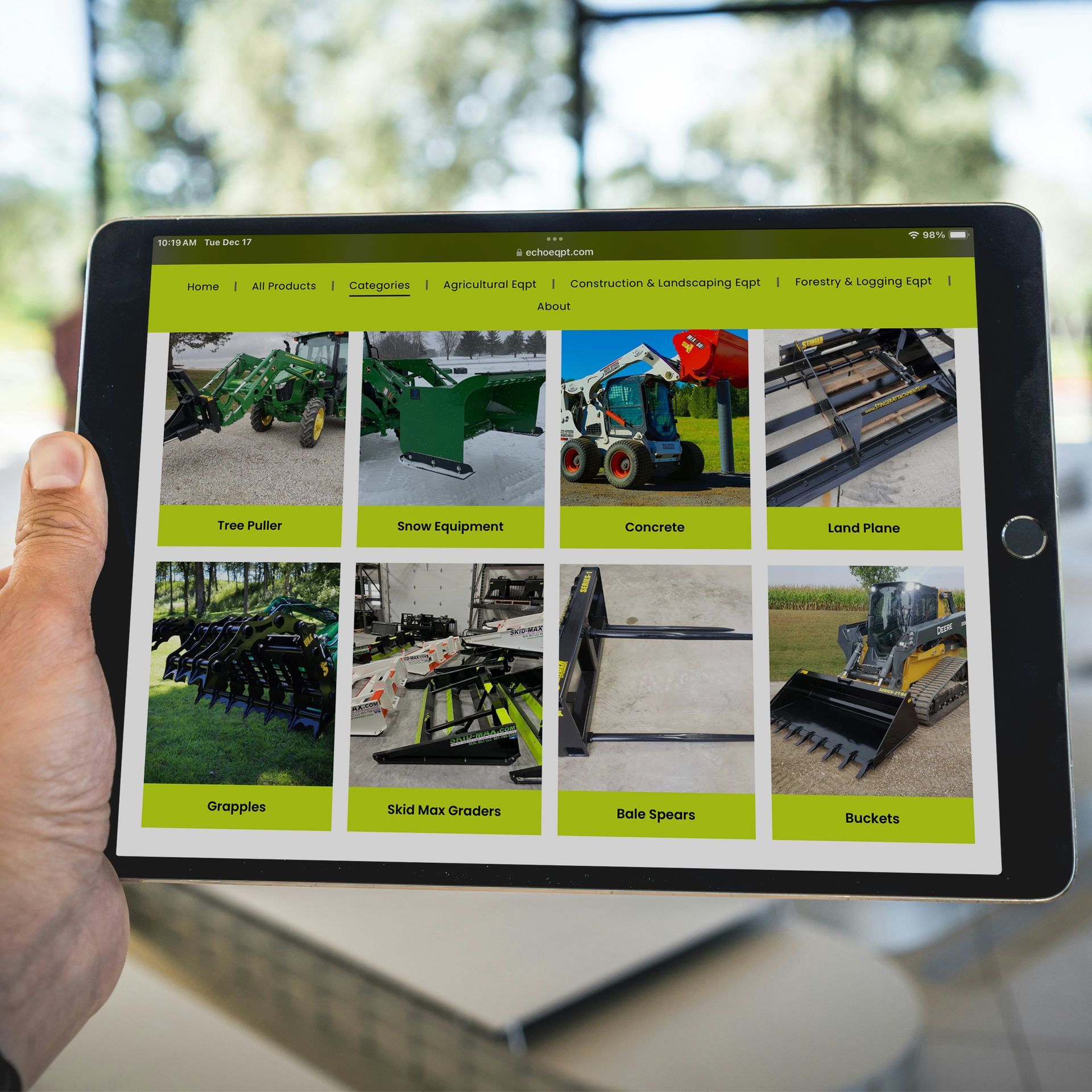 A person is holding a tablet with images of tractors on it