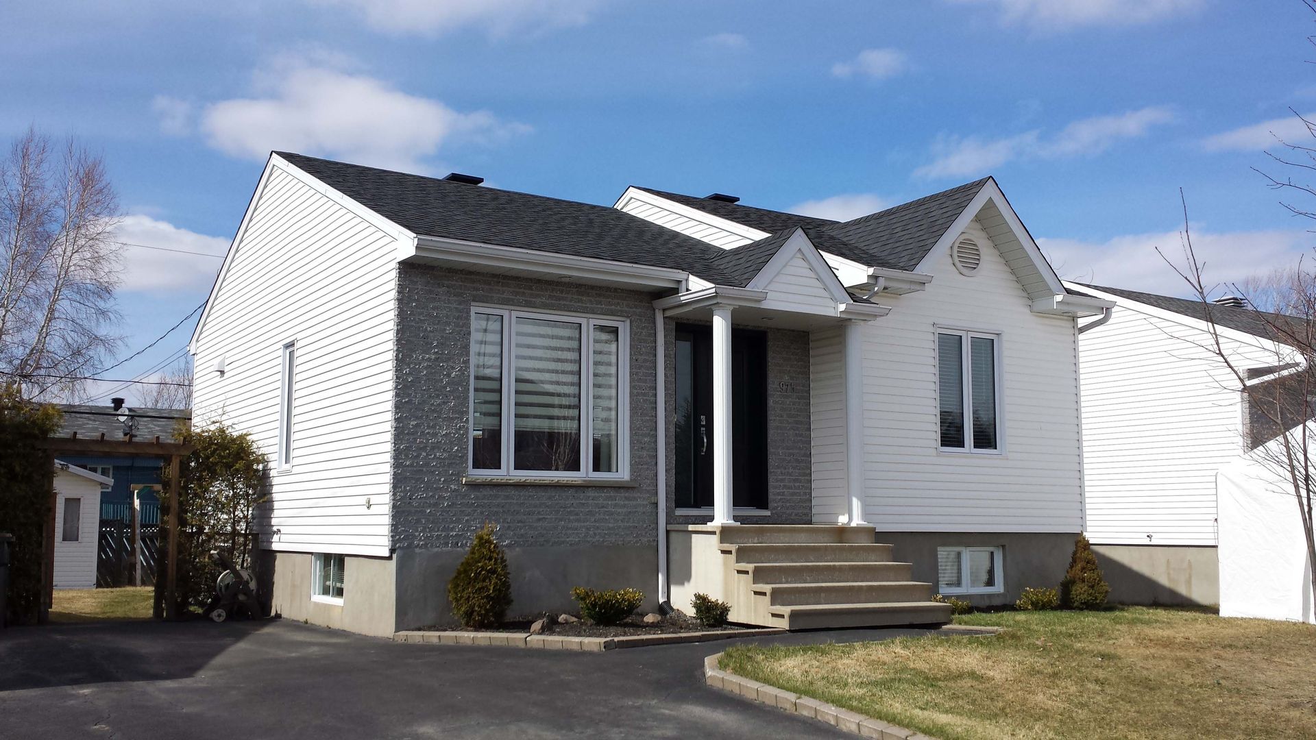 Une petite maison blanche avec un toit noir