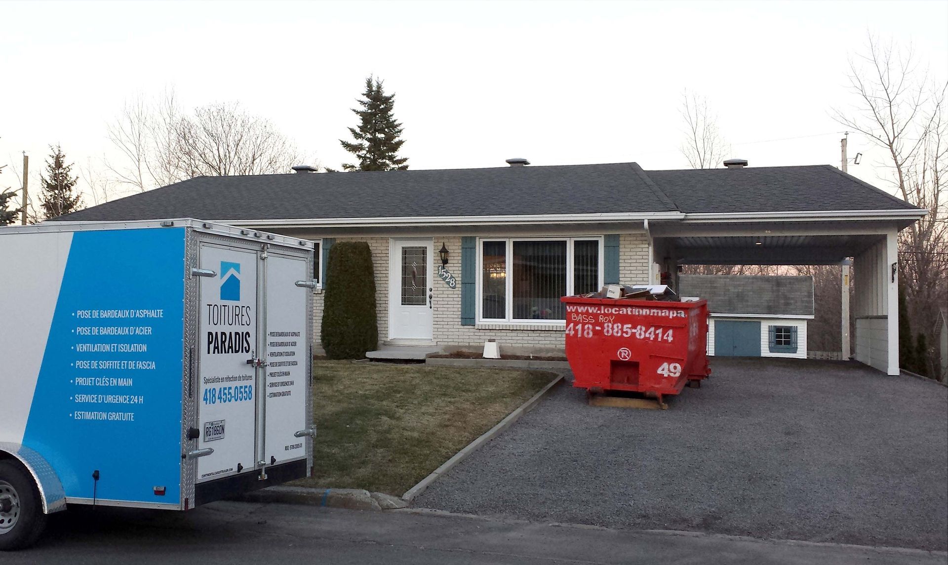 Un camion bleu et blanc est garé devant une maison.