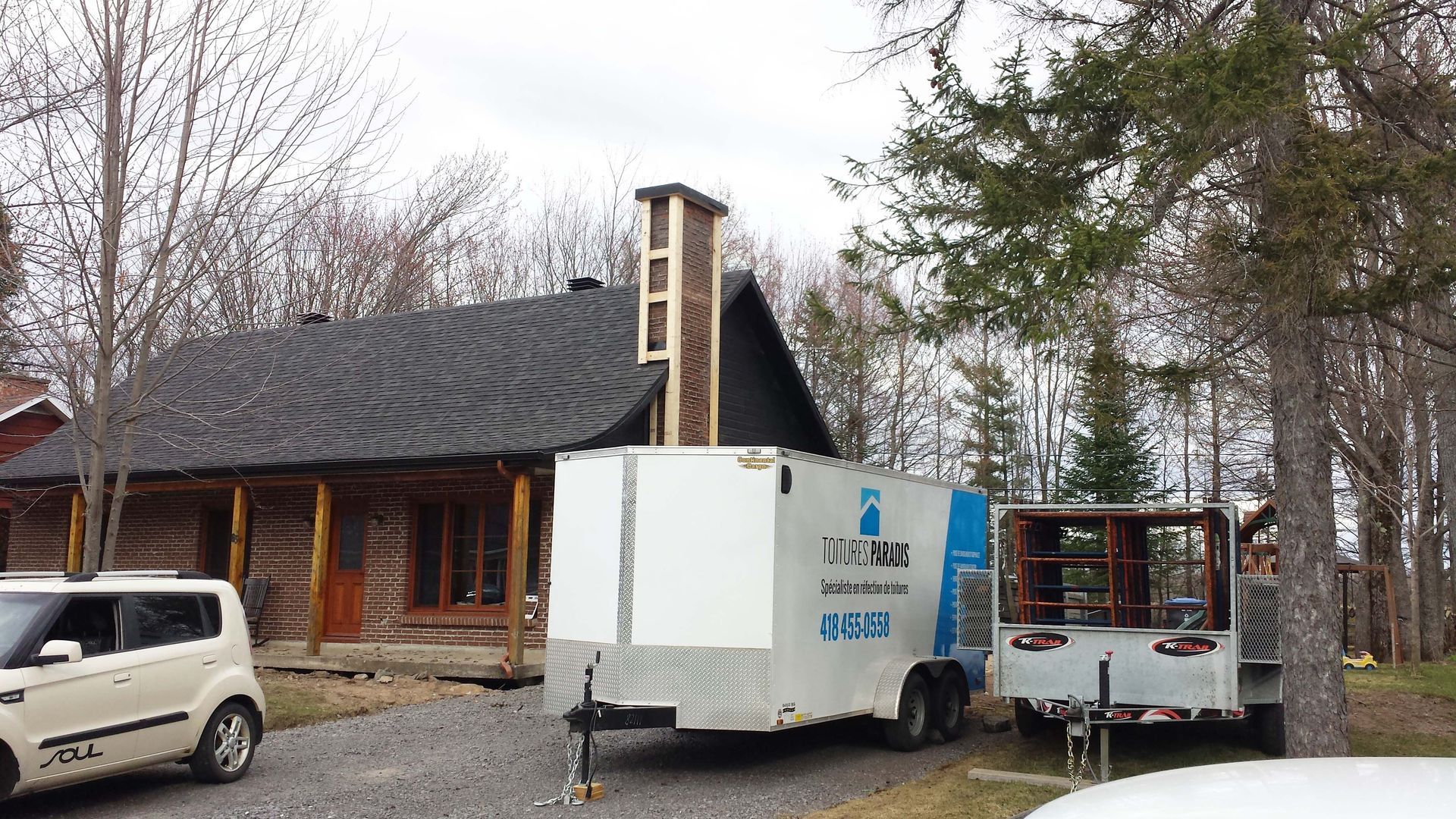 Une remorque blanche avec le mot ups dessus est garée devant une maison.
