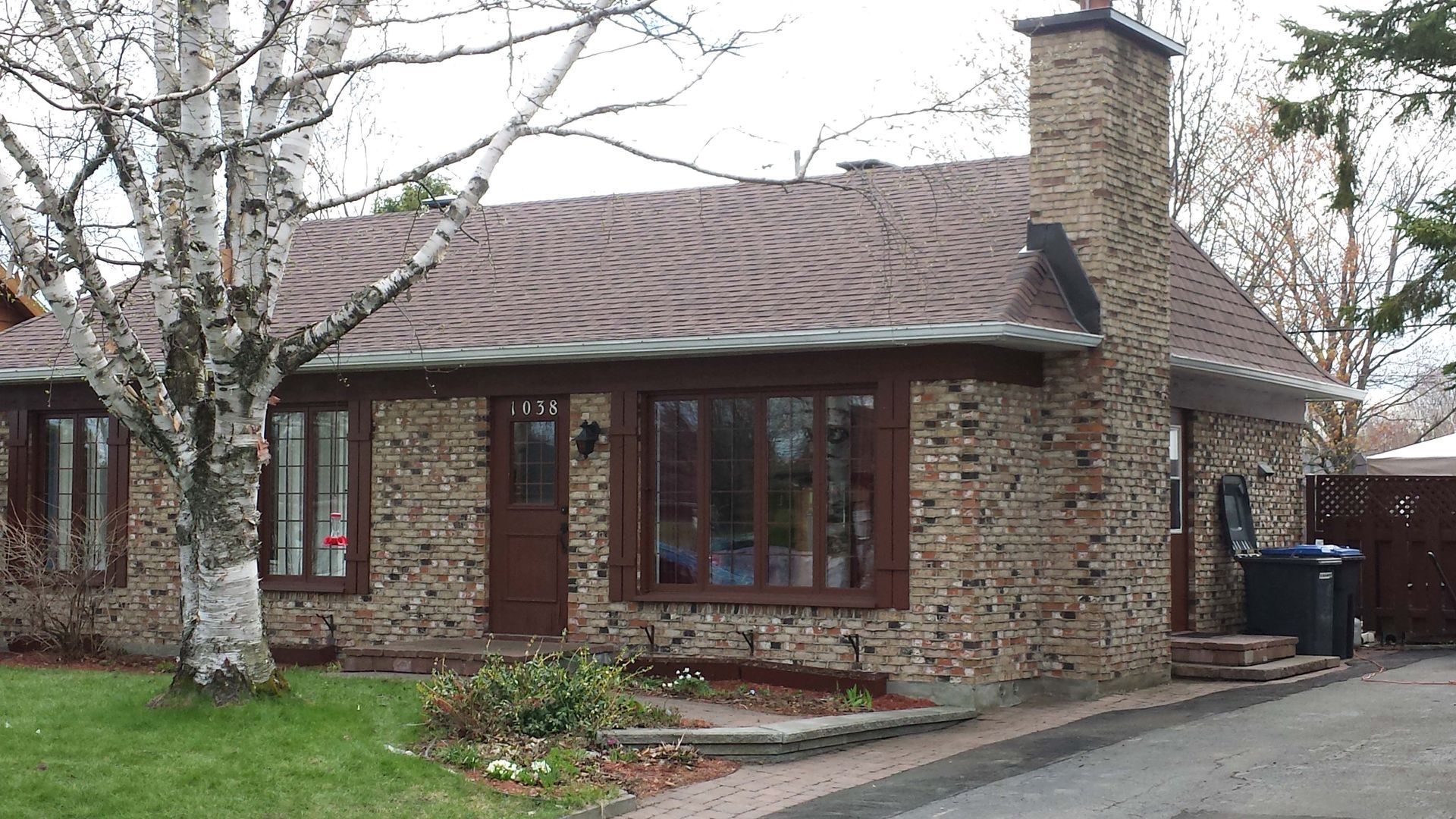 Une maison en briques avec une cheminée et beaucoup de fenêtres