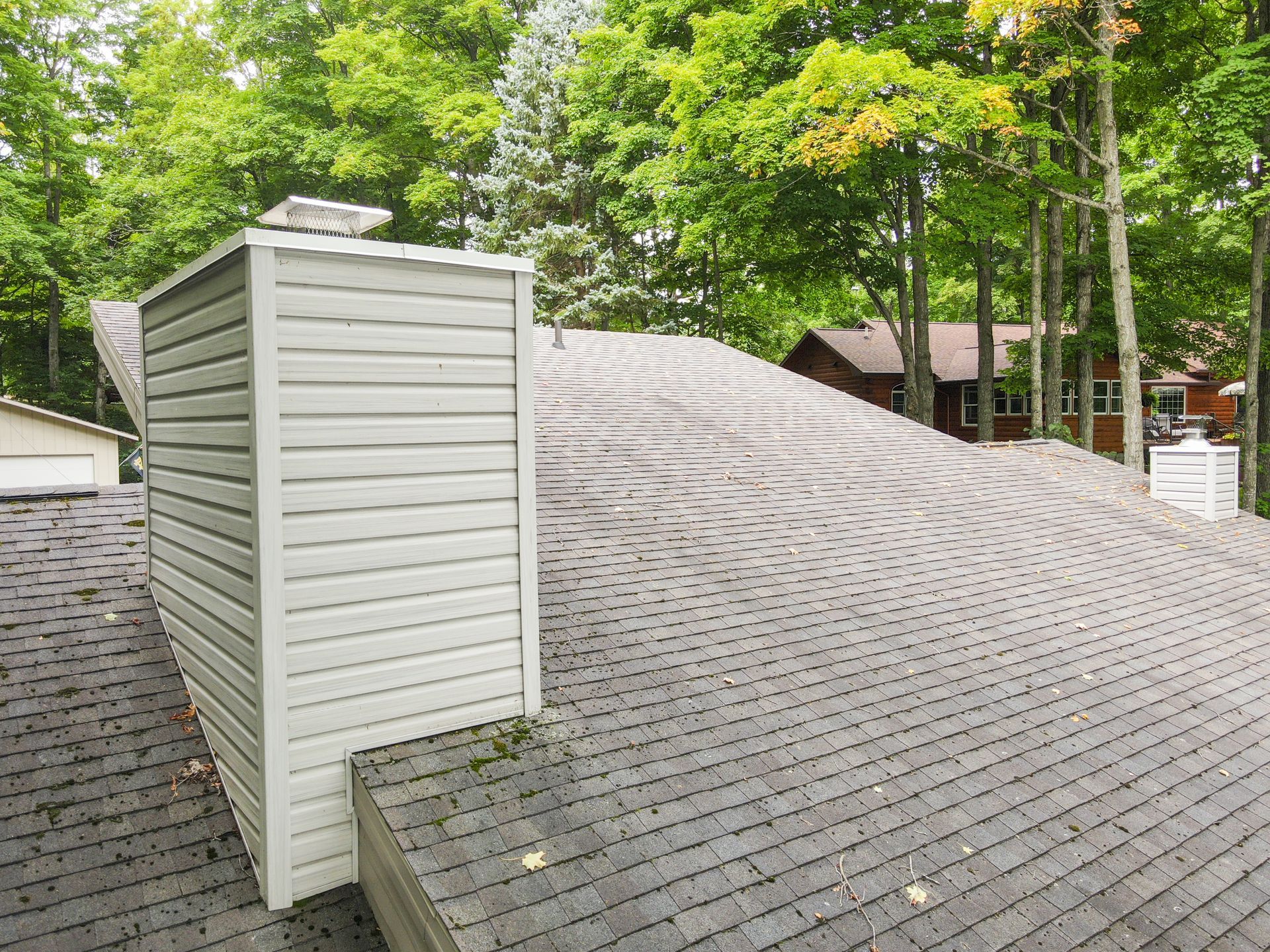 Un toit avec une cheminée dessus et des arbres en arrière-plan.