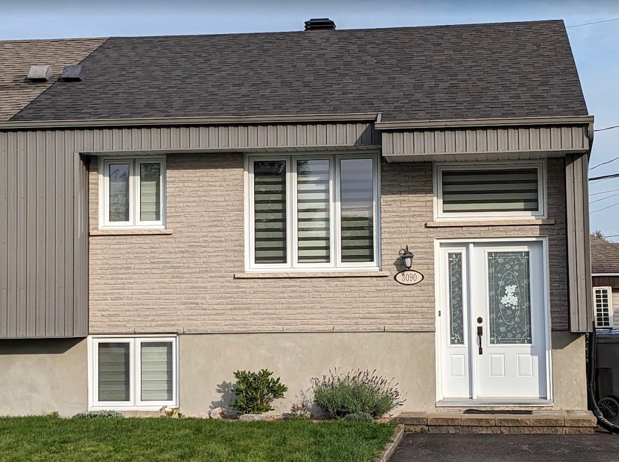Une maison en briques avec une voiture garée devant.