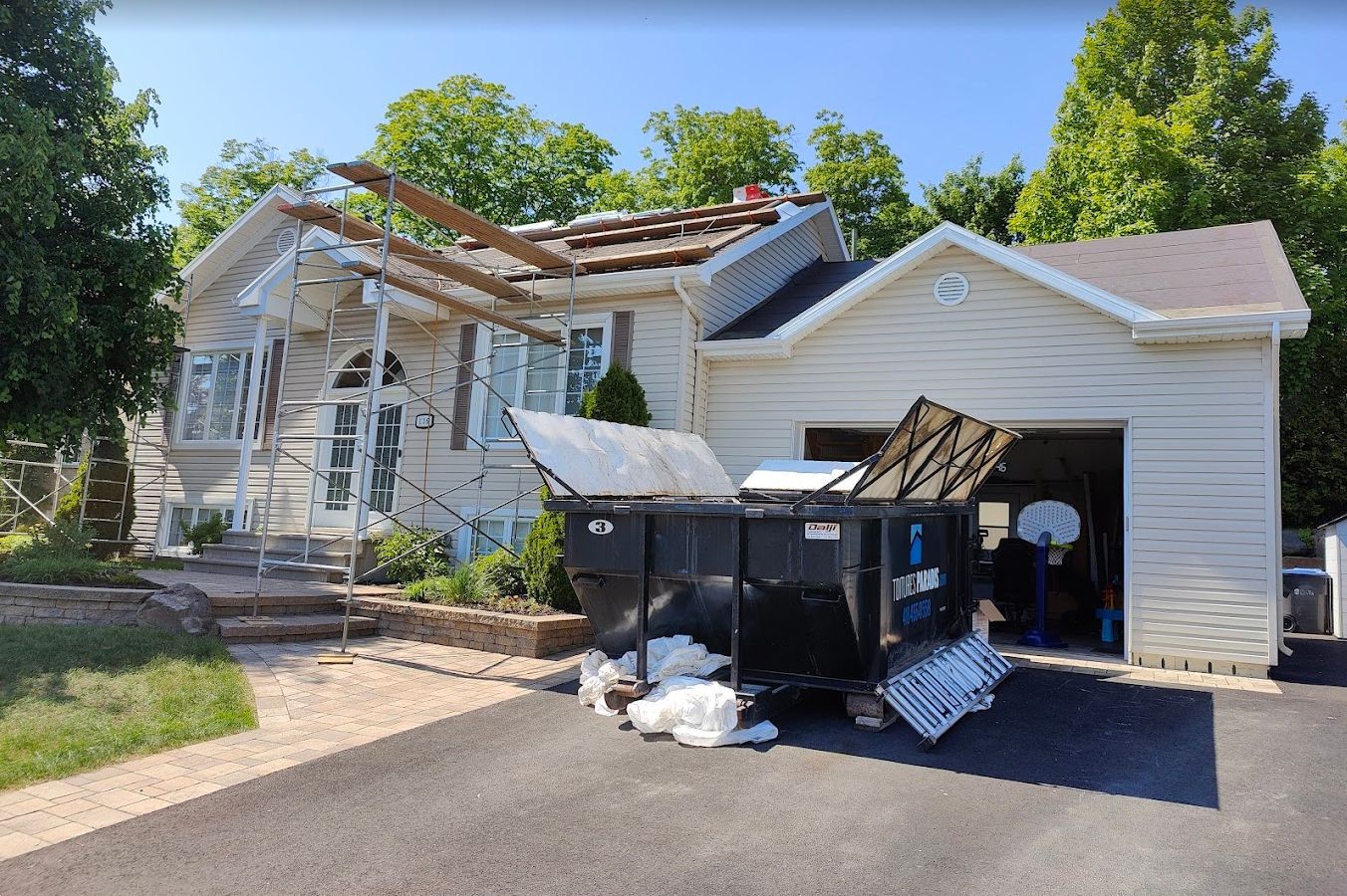 Une benne à ordures est garée devant une maison en cours de rénovation.