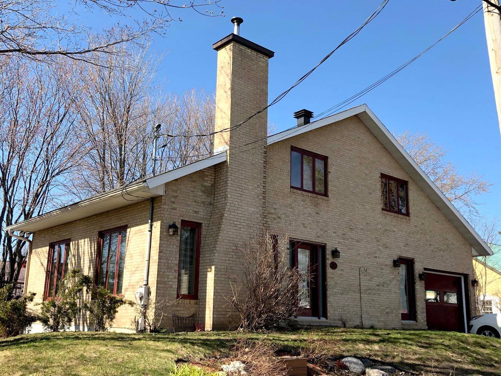 Une grande maison en briques avec une cheminée au sommet.