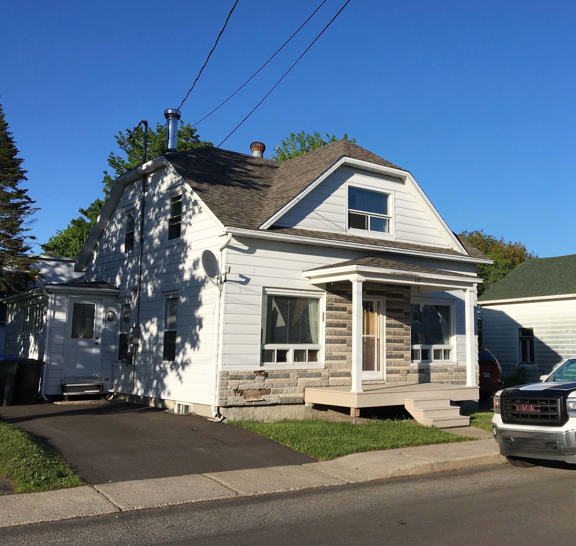 Un camion GMC est garé devant une maison blanche