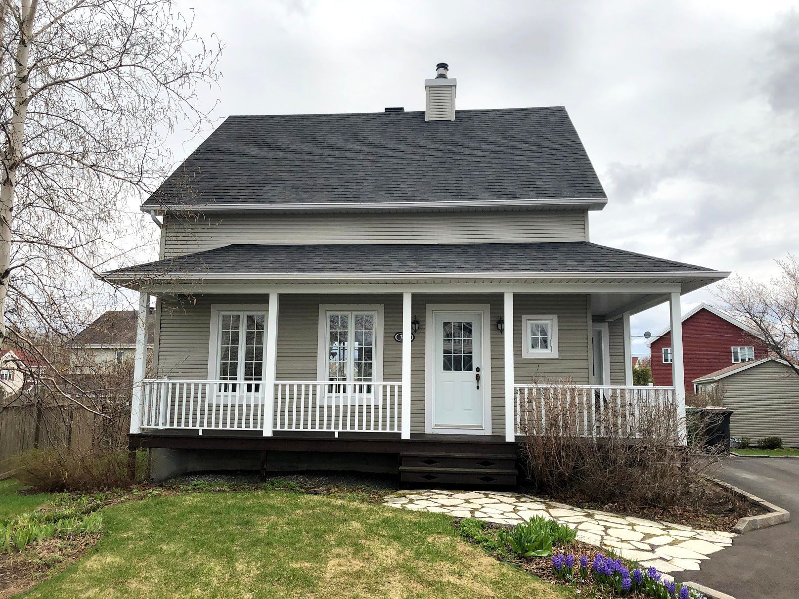 Une petite maison avec un porche et une cheminée sur le toit.