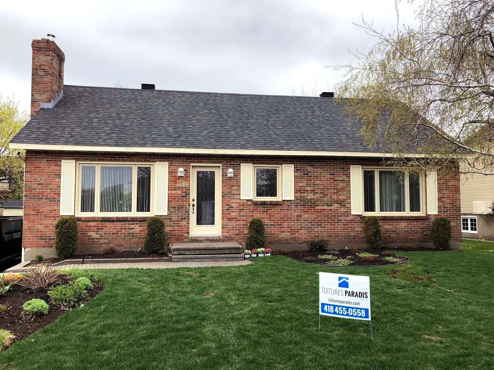 Une maison en briques avec un panneau devant.