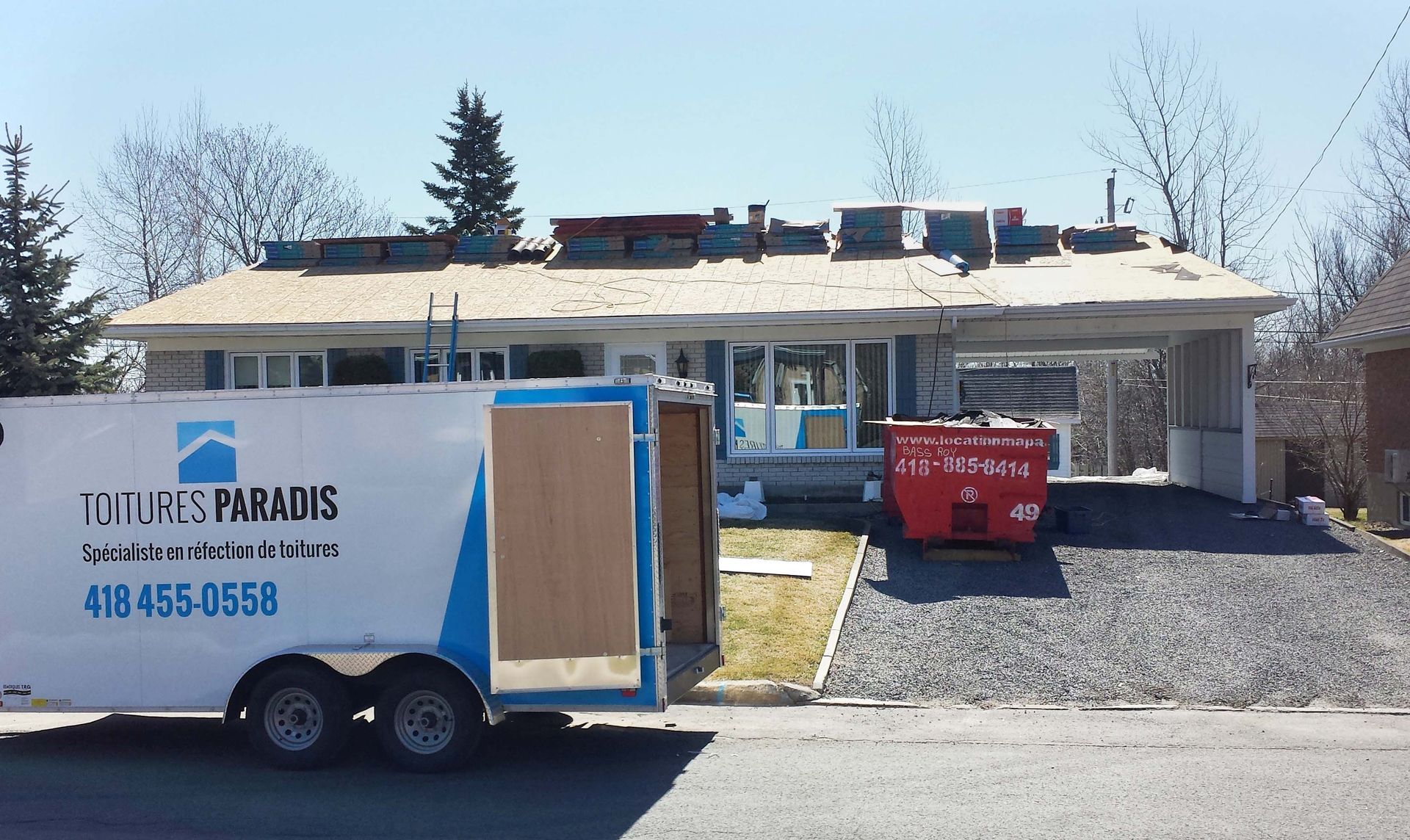 Une remorque est garée devant une maison en construction.