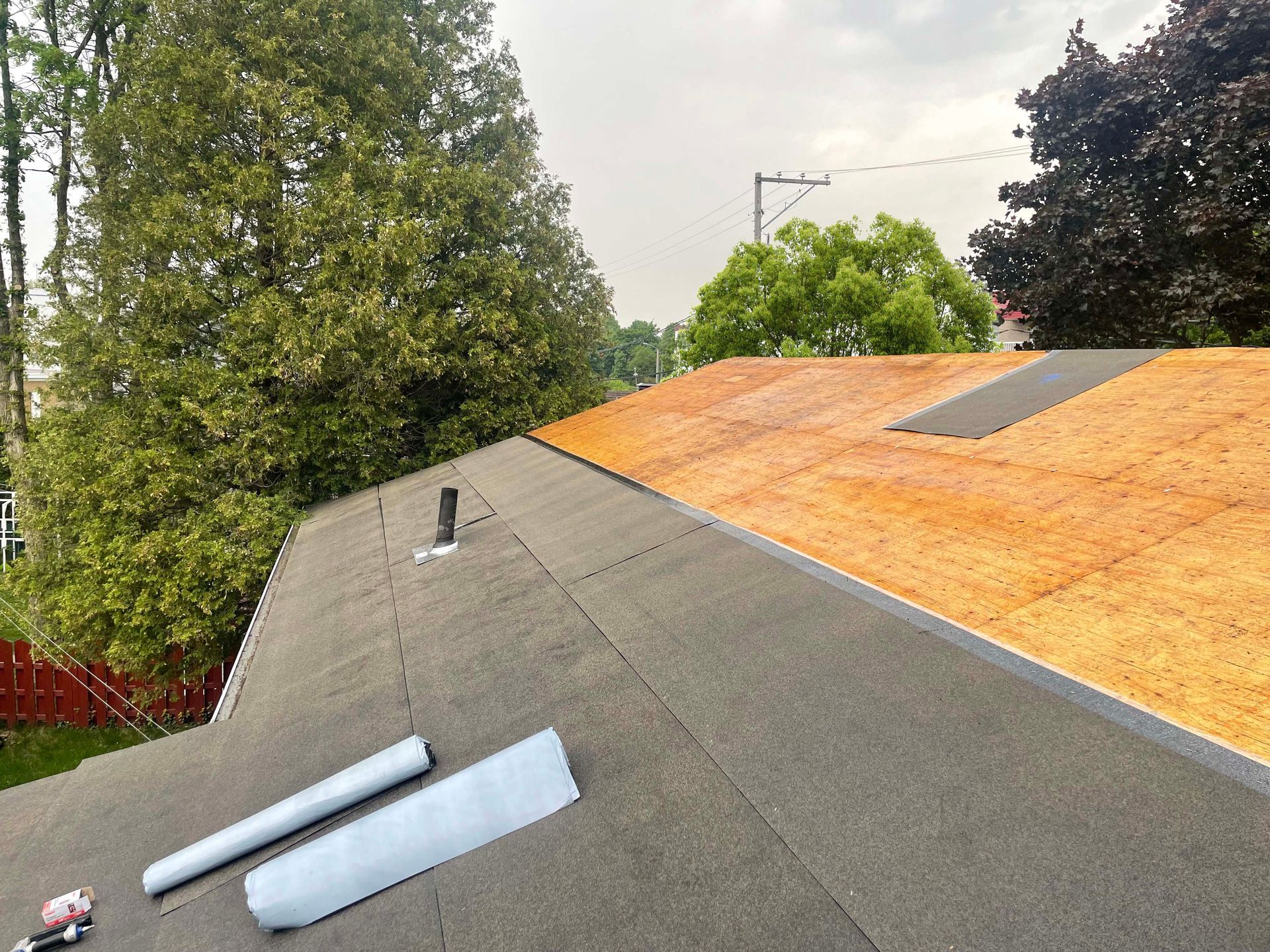 Un toit est en cours de réparation avec un rouleau de contreplaqué dessus.