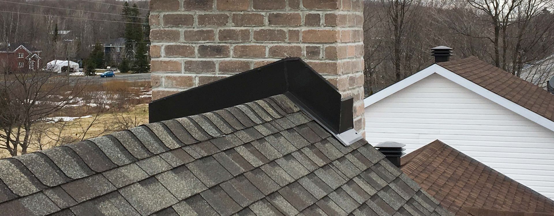 Un toit de maison avec une cheminée et un mur de briques.