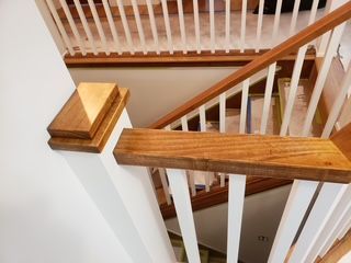 Person painting a white ceiling with a paint roller; blue tape and tarp protect surrounding areas.