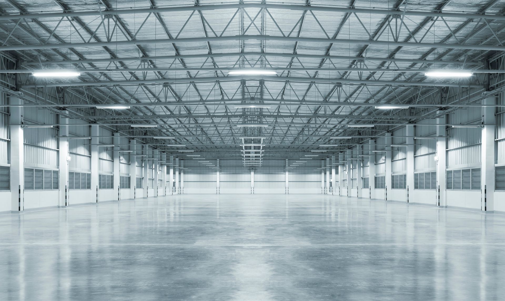 Empty, industrial warehouse interior with concrete floor and metal framework.