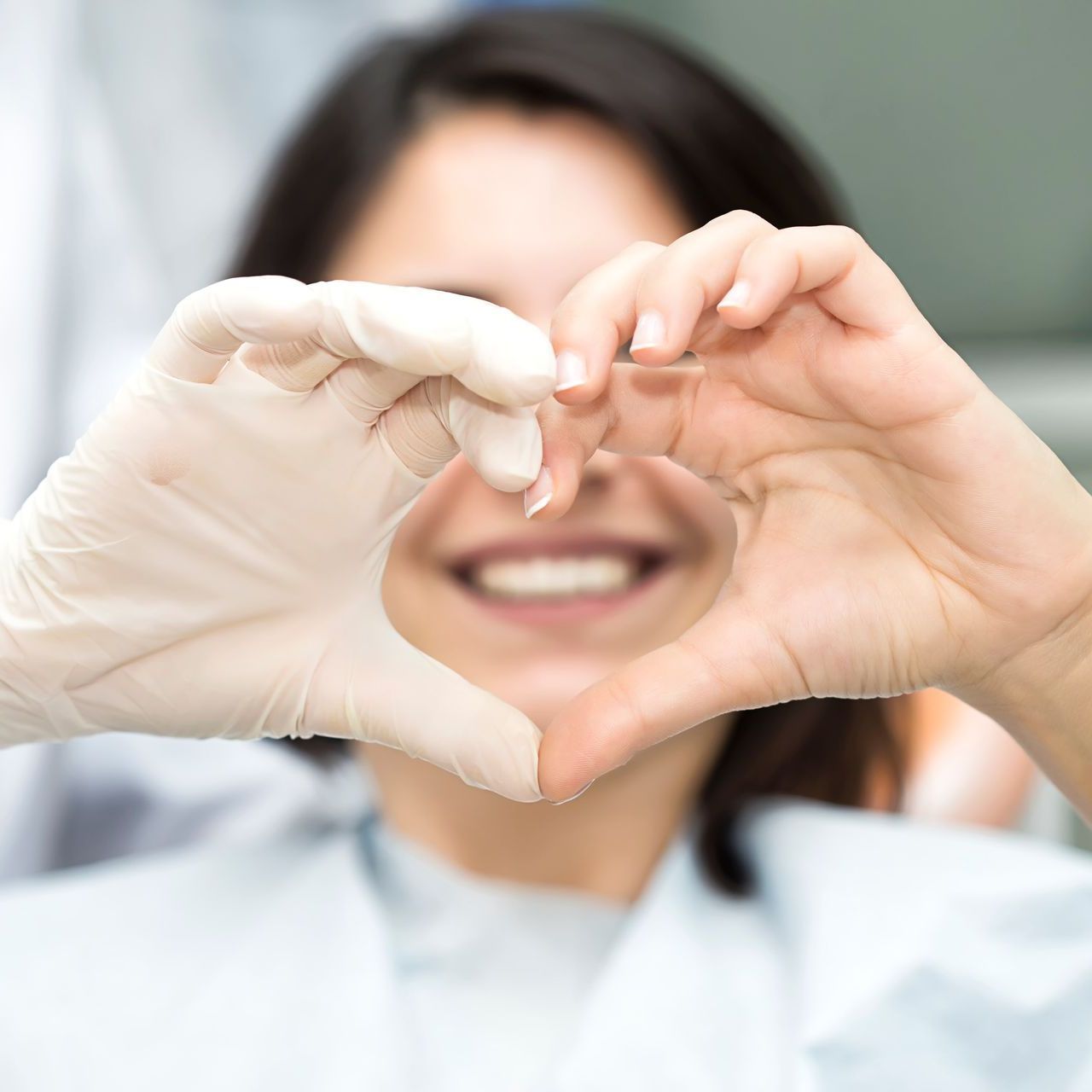 A woman wearing gloves is making a heart shape with her hands