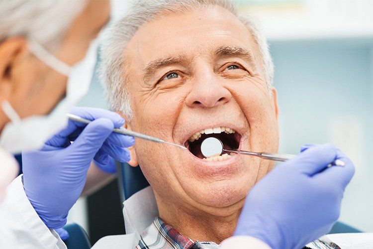 An elderly man is having his teeth examined by a dentist.