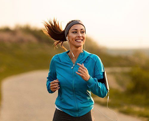 women with blue shirt and headphones with road behind her