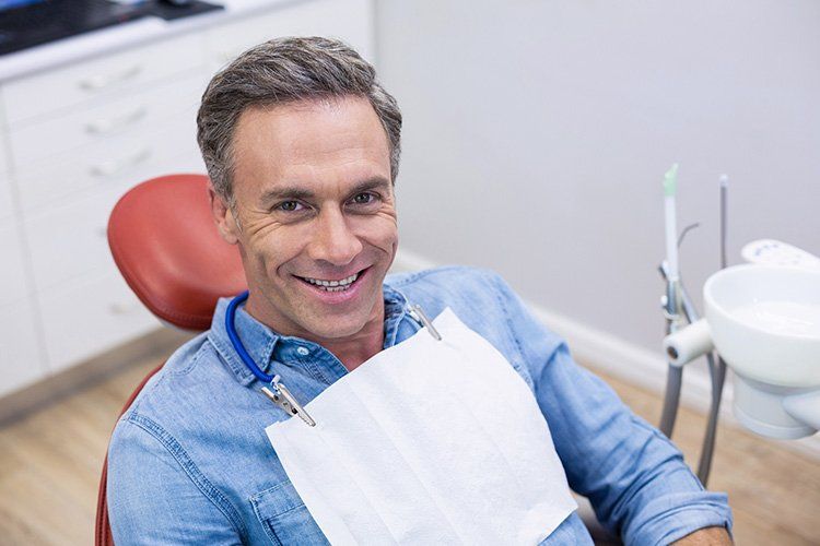 A man is smiling while sitting in a dental chair.