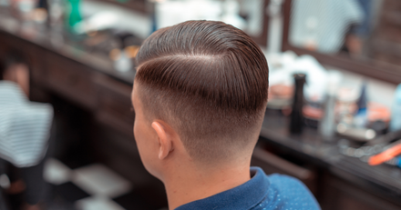 A man is getting his hair cut by a barber in a barber shop.