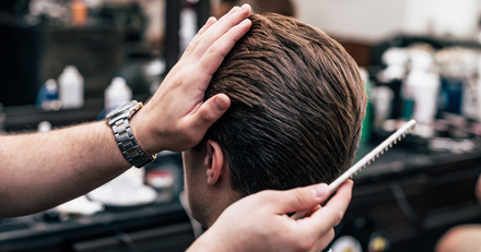 A man is getting his hair cut by a barber in a barber shop.