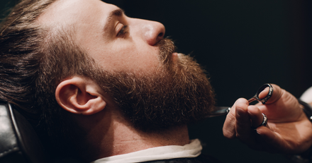 A man is getting his beard shaved by a barber.