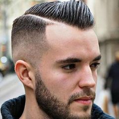 A man with a beard wearing a black shirt is touching his hair