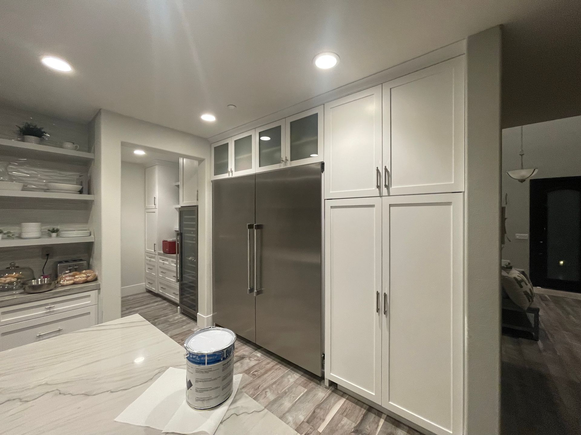 A kitchen with white cabinets and a stainless steel refrigerator.