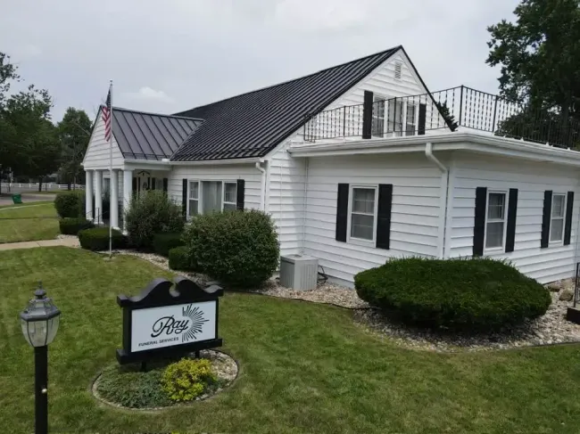 The front door of a house with a porch and plants in front of it.