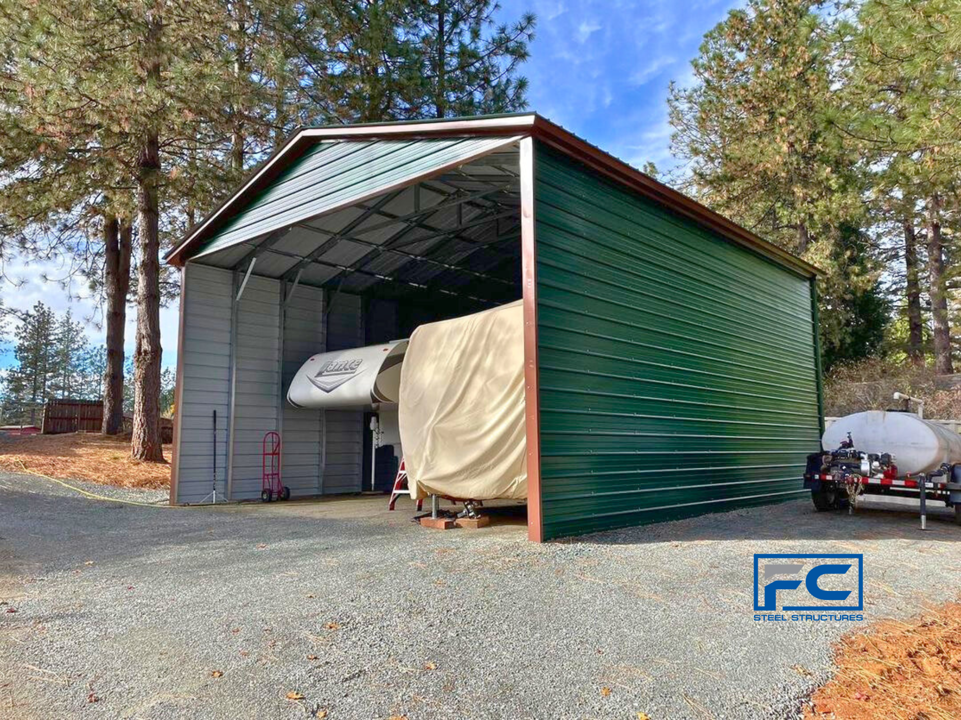 A green metal garage with a trailer inside of it.