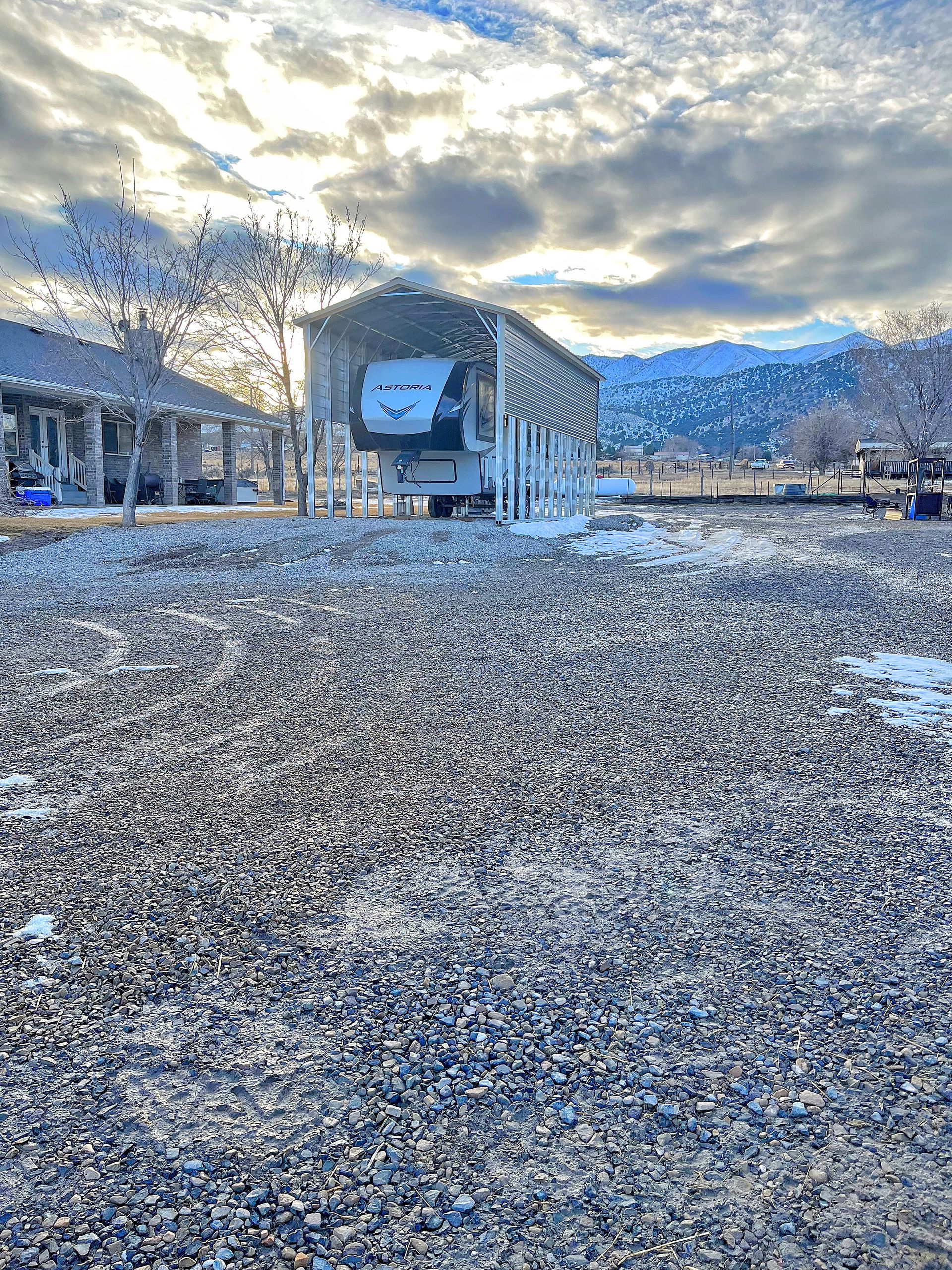 A trailer is parked in a gravel lot in front of a building.