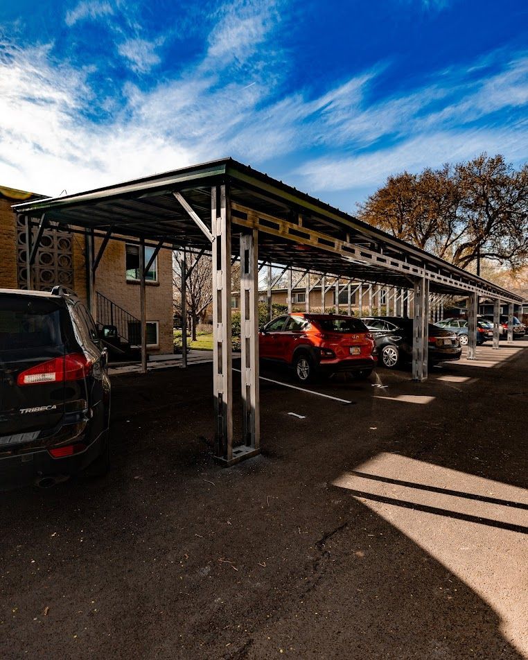 A parking lot with cars parked under a lean to structure