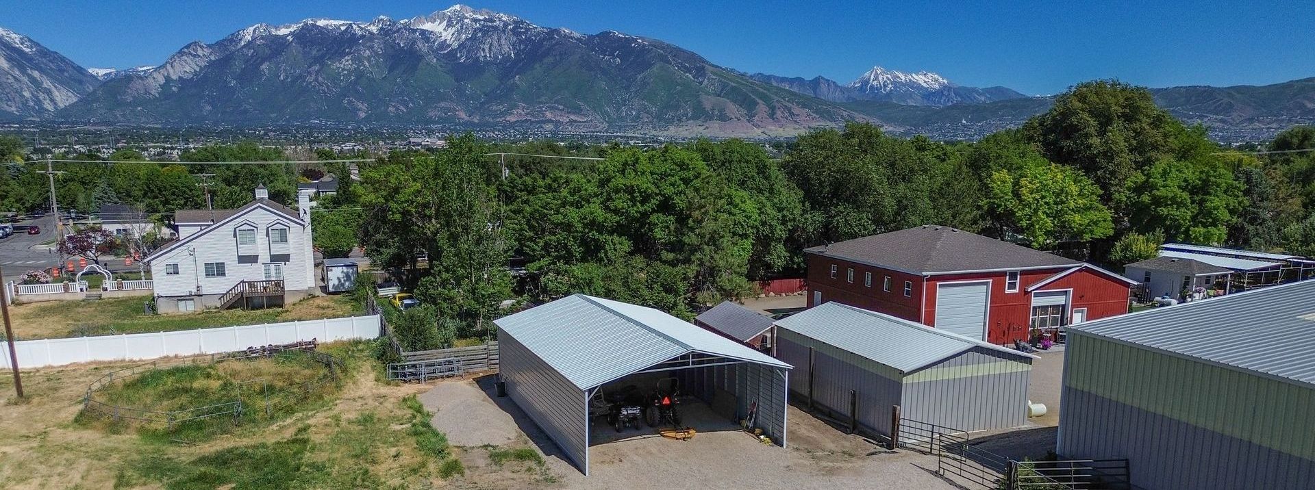 Durable steel structures by FC Steel, including a metal carport, barn, and garage, built for all-weather protection and long-lasting performance.