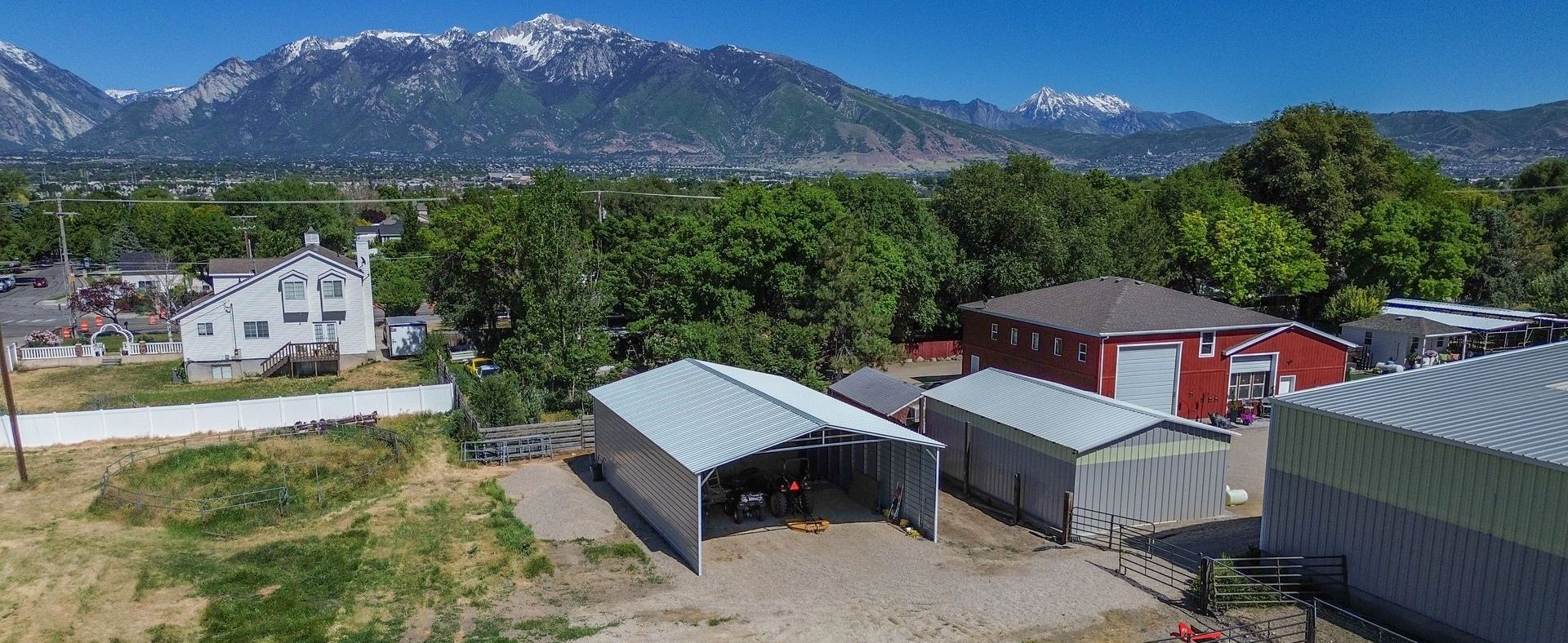 Durable steel structures by FC Steel, including a metal carport, barn, and garage, built for all-weather protection and long-lasting performance.