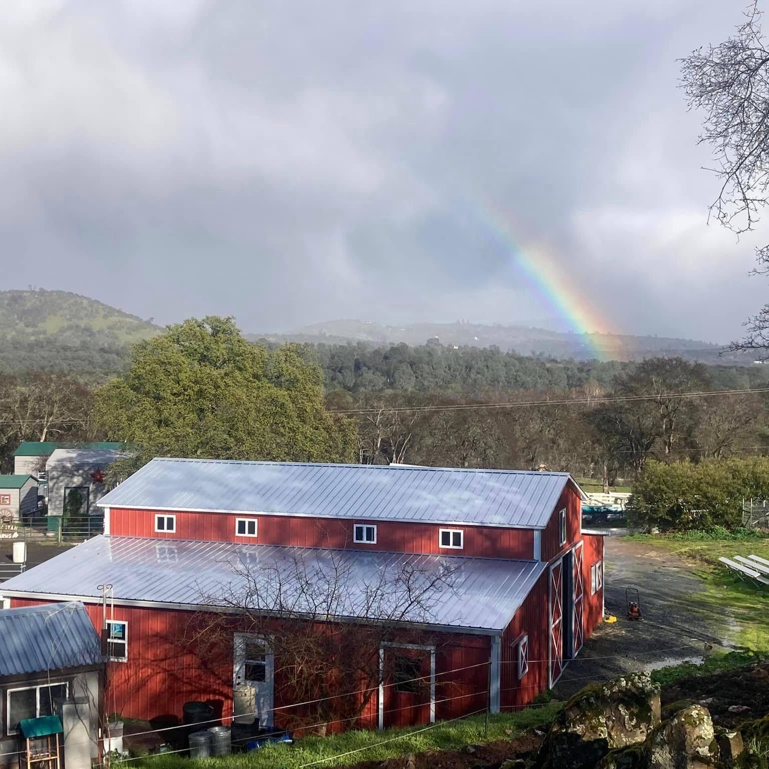 A red barn with a rainbow in the background