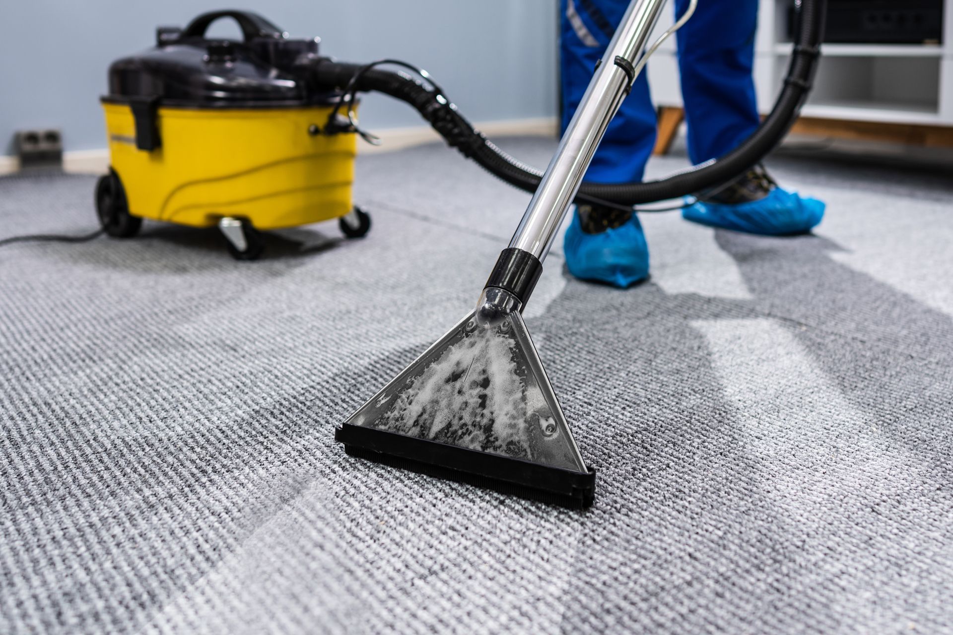 A person is cleaning a carpet with a vacuum cleaner.