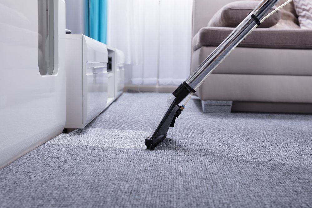 A Vacuum Cleaner Is Cleaning a Carpet in A Living Room — Turbo Clean in Tuncurry, NSW