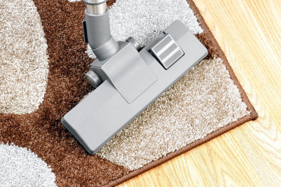 A Vacuum Cleaner Is Cleaning a Rug on A Wooden Floor — Turbo Clean in Tuncurry, NSW