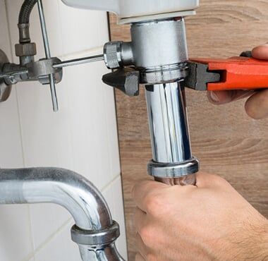 Male Plumber Fixing Sink In Bathroom — Plumbing Repair in Tucson, AZ