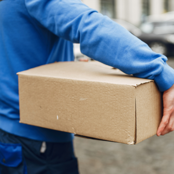 A man in a blue shirt is holding a cardboard box