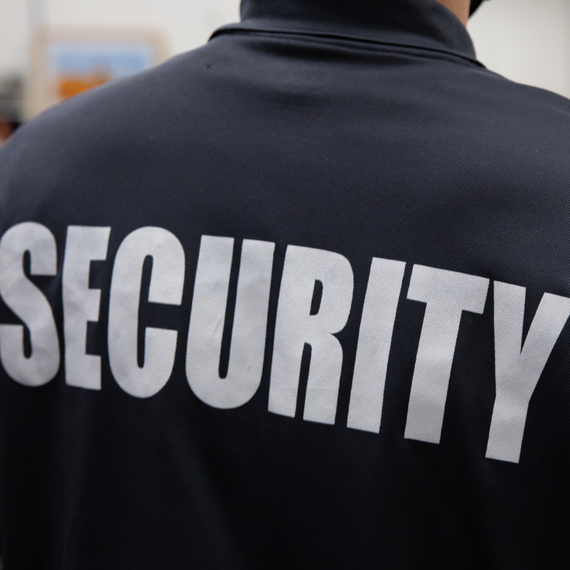 A man wearing a black jacket with the word security on the back